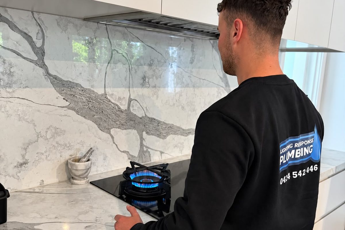 Licensed gas fitter checking the flame on a newly connected gas cooktop in a Melbourne kitchen