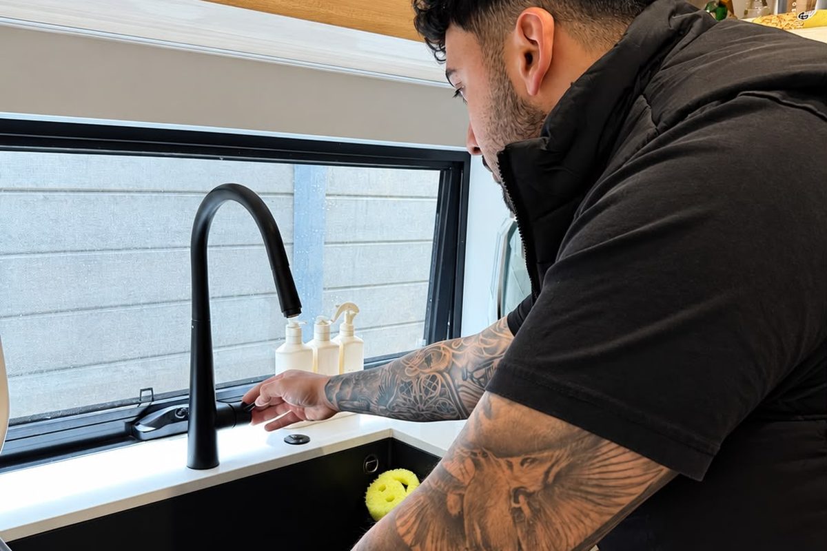 Plumber repairing a black kitchen mixer tap at a Melbourne home